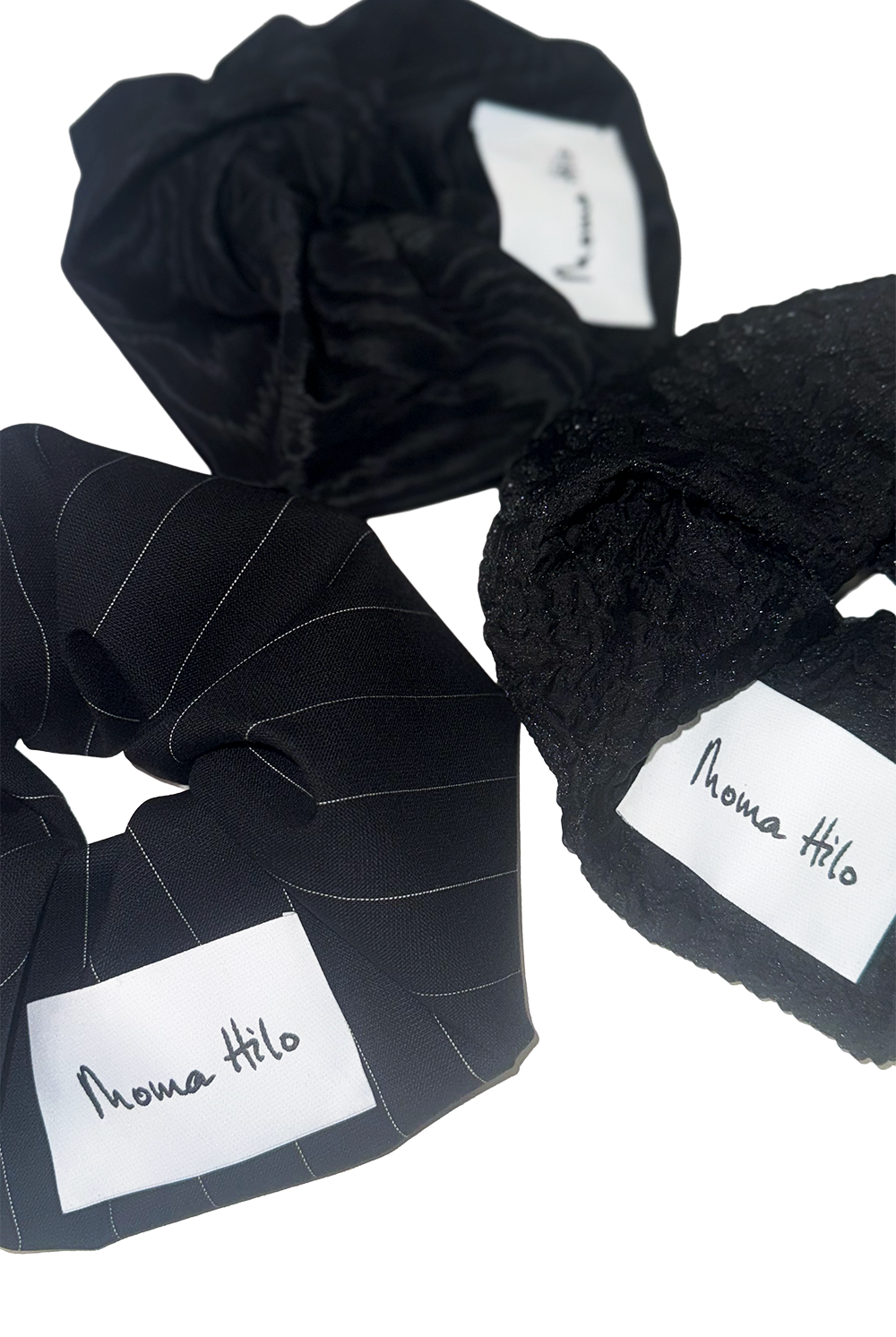 Black scrunchies with 'Moma Hilo' labels on a white background