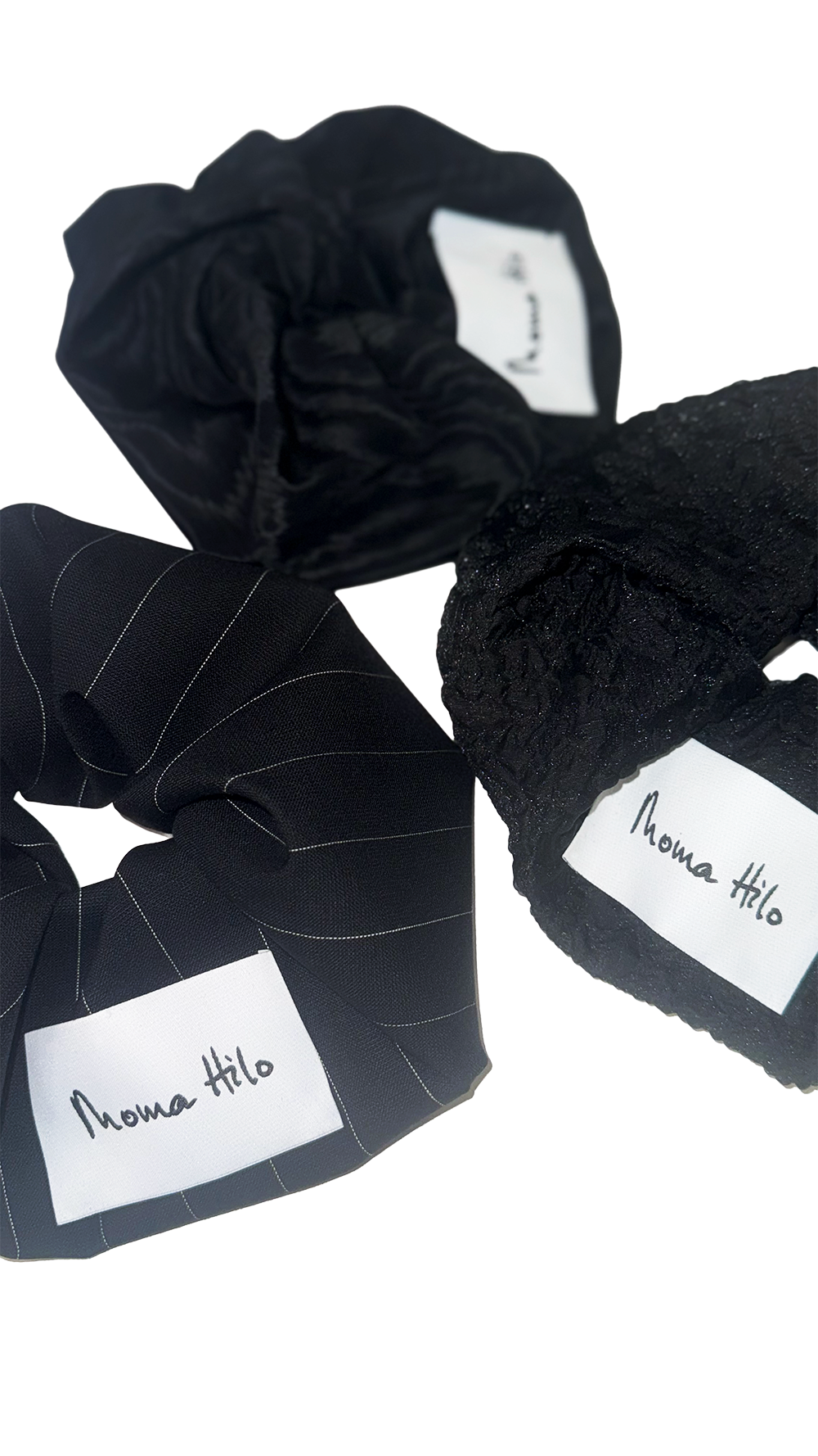 Black scrunchies with 'Moma Hilo' labels on a white background
