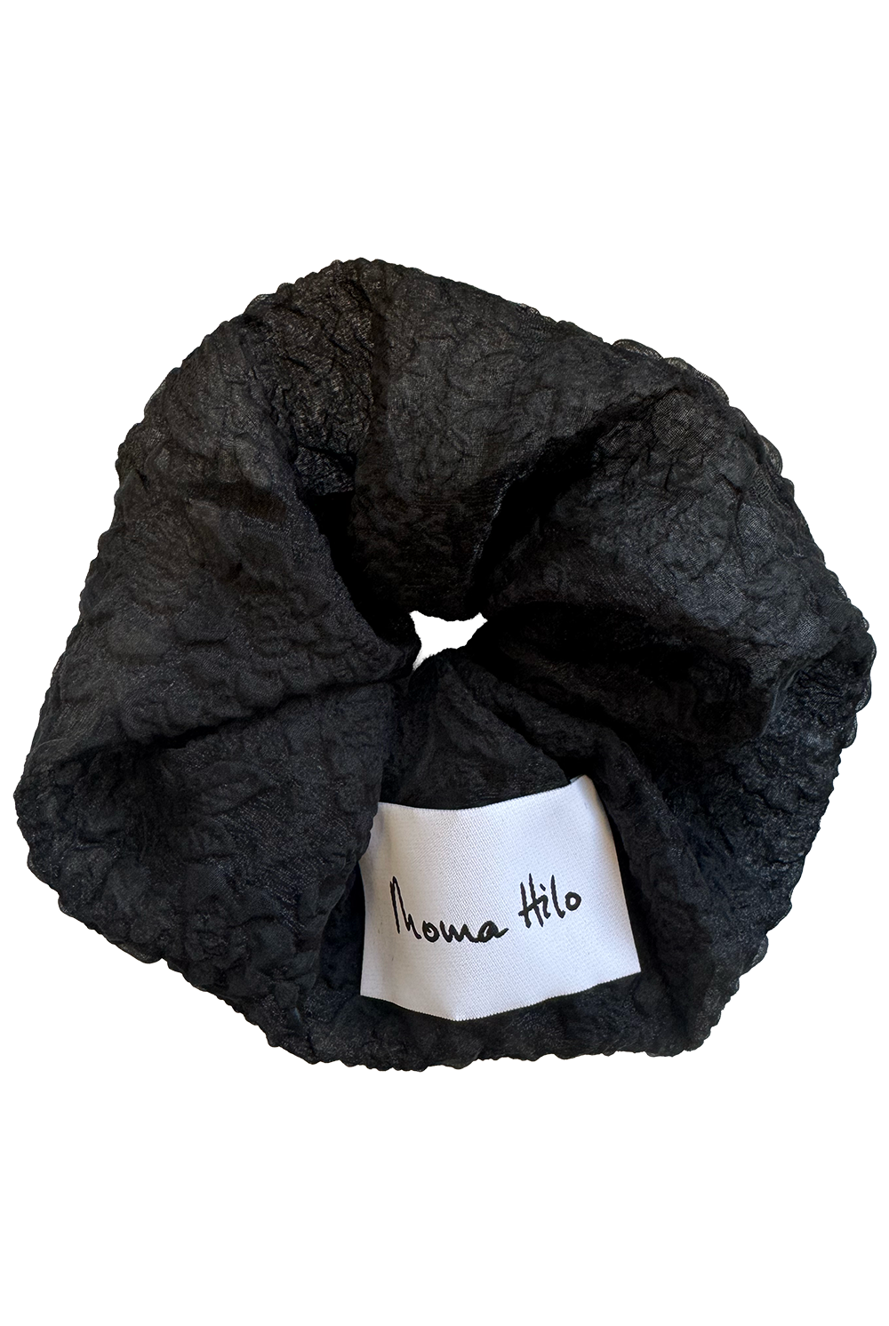 Black textured scrunchie with a white label on a white background