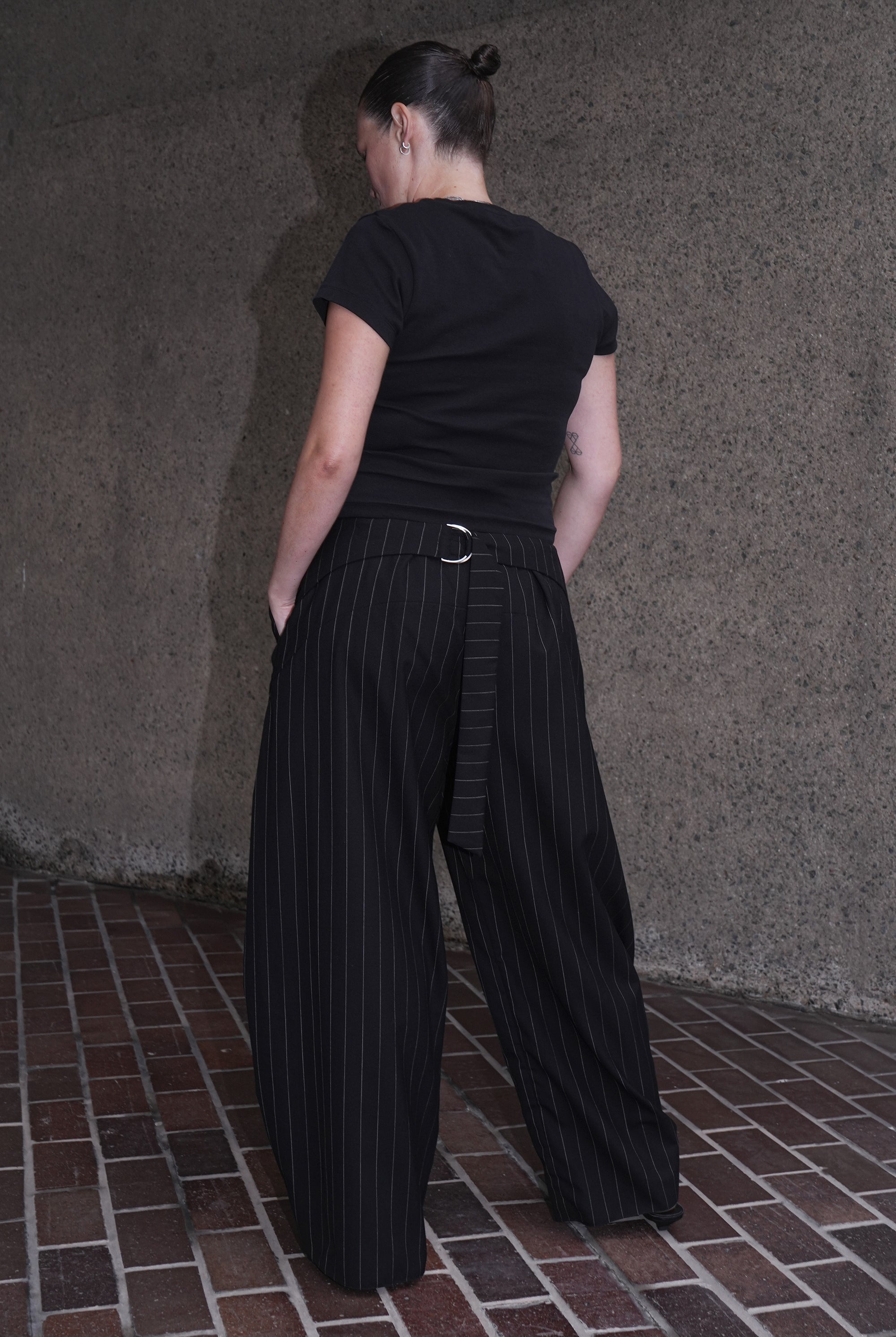 MODEL WEARING BLACK PINSTRIPE WOOL TROUSERS IN DEADSTOCK FABRIC - BACK VIEW
