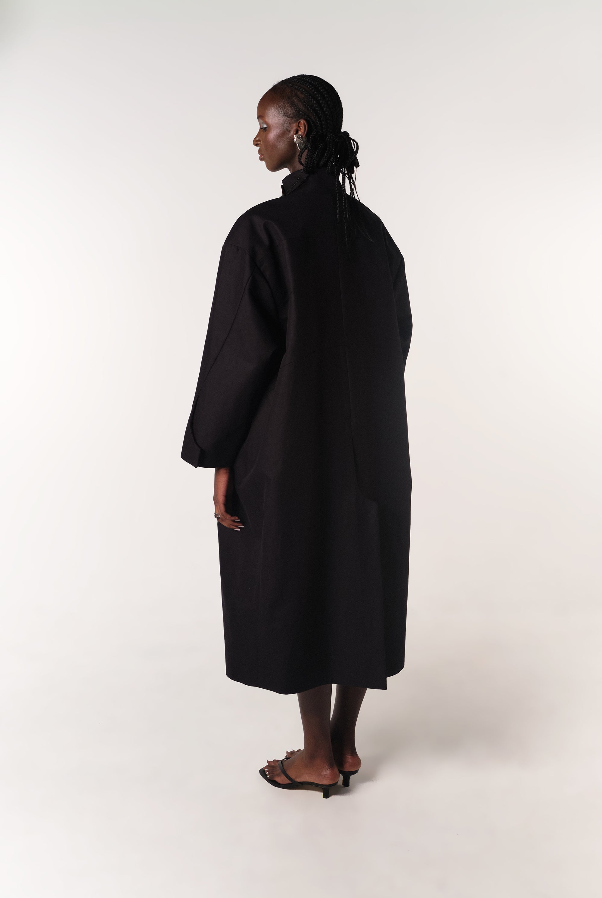 MODEL WEARING BLACK DEADSTOCK COTTON HILDA COAT SHOWING BACK DETAILS