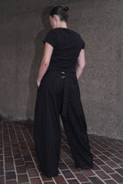 MODEL WEARING BLACK PINSTRIPE WOOL TROUSERS IN DEADSTOCK FABRIC - BACK VIEW