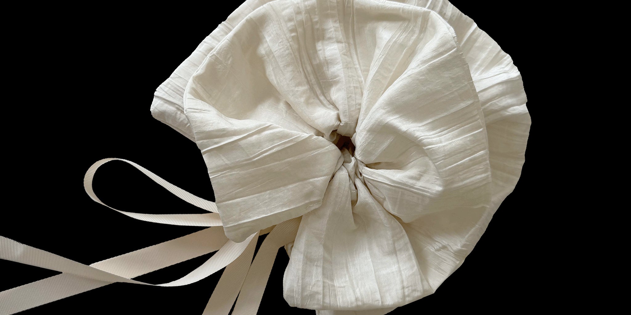 Ivory fabric hair tie with ribbons on a black background